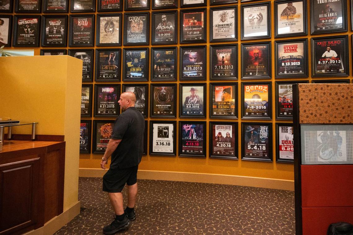 Travis O'Guin standing near a wall of Strange Music artist posters